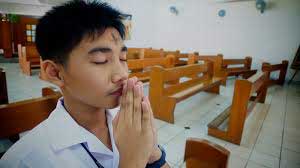 Young man with ash cross on face praying