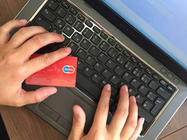 Person shopping on laptop with credit card out and ready to go.