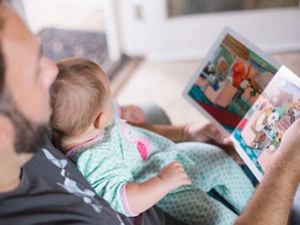 Father reading story book to baby daughter.
