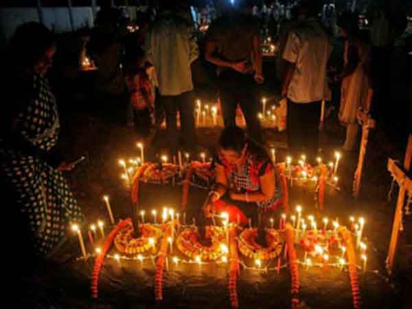 Lighting candles on graves prior to praying on All Souls’ Day.